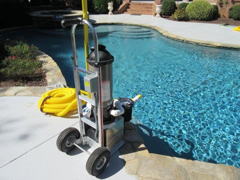 Pool Weasel system beside a curved backyard pool with stone coping