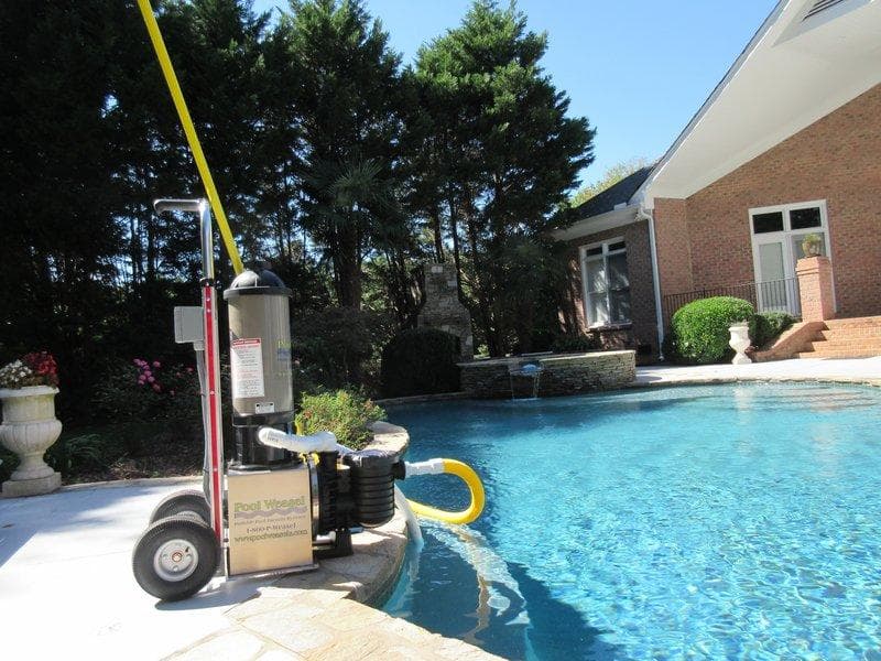 Pool Weasel system beside a backyard pool with a raised spa and brick home
